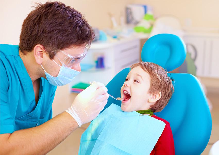 Dentista sonriente atendiendo a un niño en una clínica luminosa